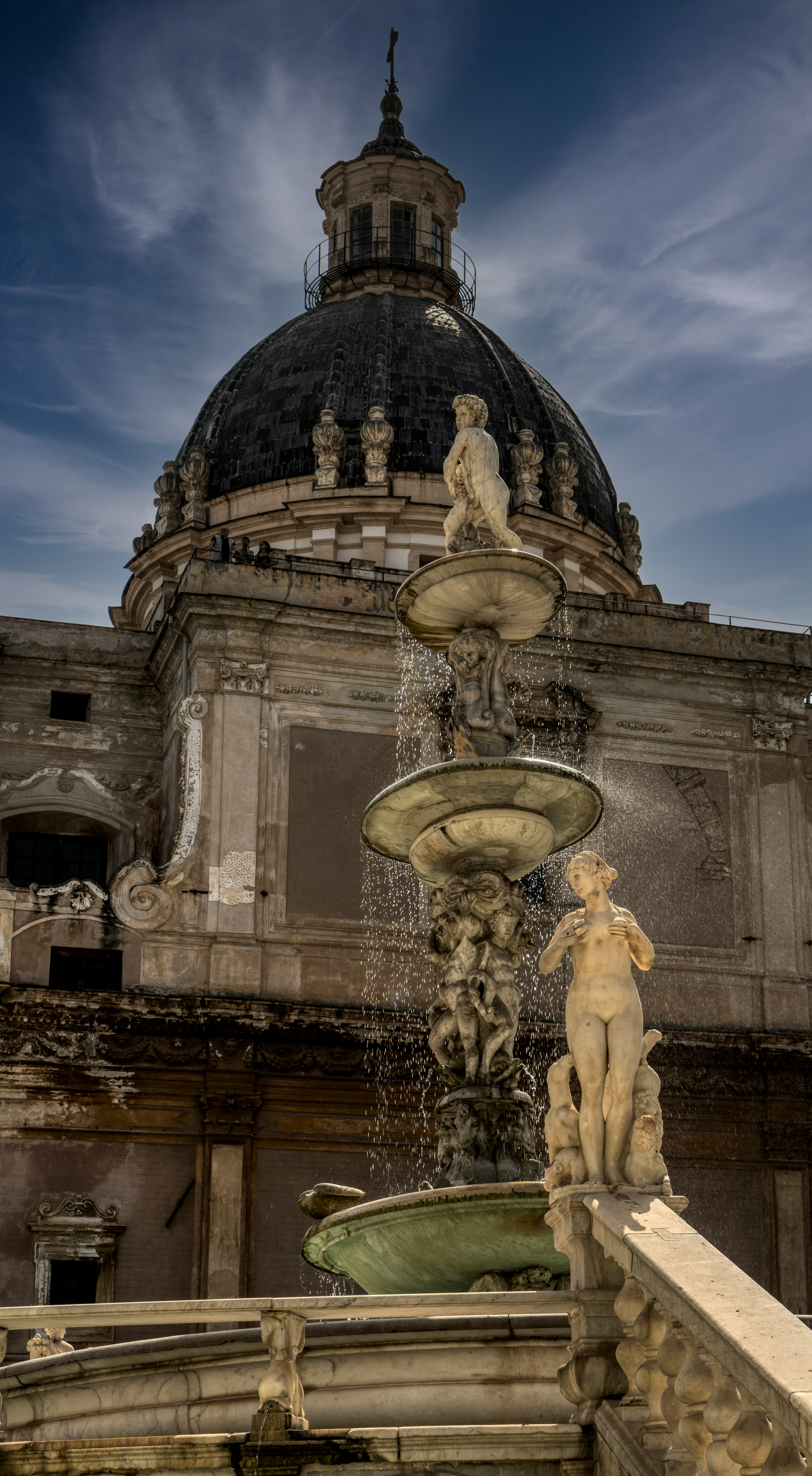 gold statue fountain in front of gray concrete building during night time